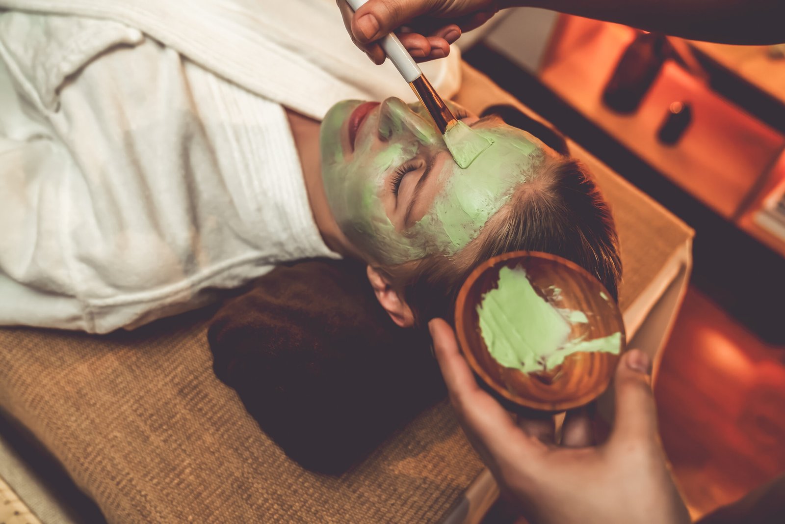 Serene ambiance of spa salon, woman customer indulges in rejuvenating with luxurious face cream massage with warm lighting candle. Facial skin treatment and beauty care concept. Quiescent